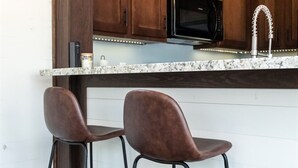 Una cocina con armarios de madera, un microondas negro y un grifo de acero inoxidable.