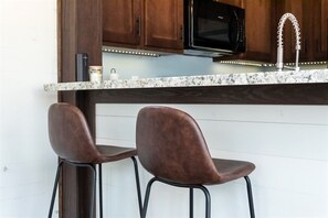 A kitchen with wooden cabinets, a black microwave, and a stainless steel faucet.