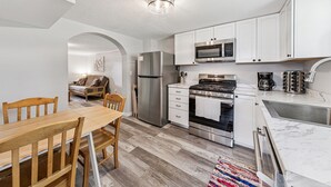 Una cocina moderna con armarios blancos, electrodomésticos de acero inoxidable y una mesa de comedor de madera.