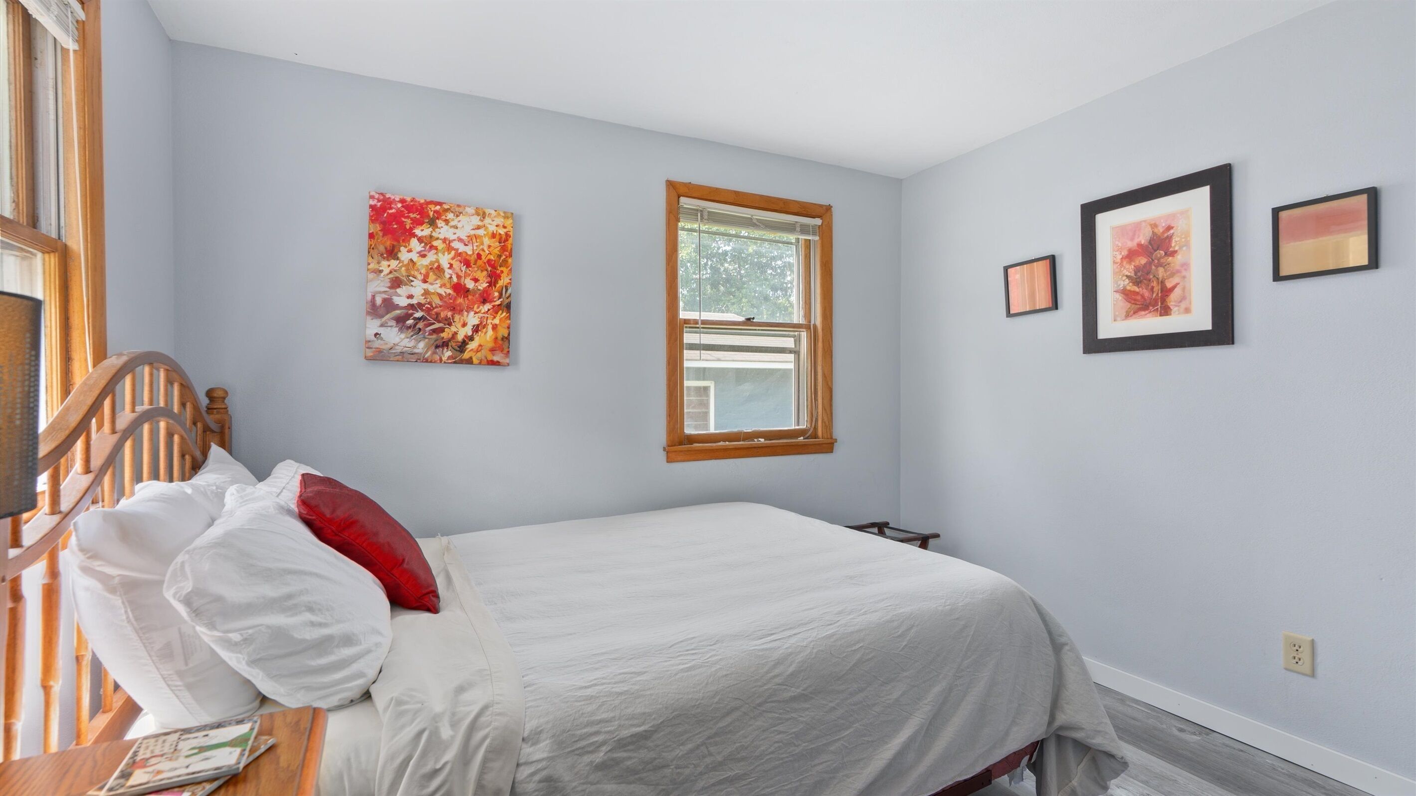Un dormitorio con una cama, una ventana y tres cuadros en la pared.