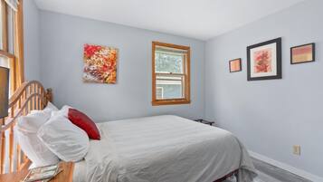 Un dormitorio con una cama, una ventana y tres cuadros en la pared.