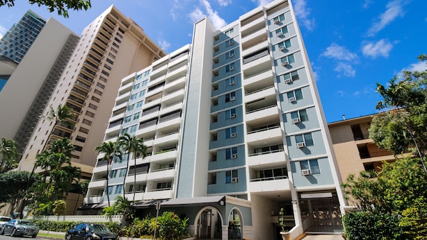 A multi-story hotel with a central entrance, balconies, and a parking area. - Spacious 2br Waikiki (Honolulu)