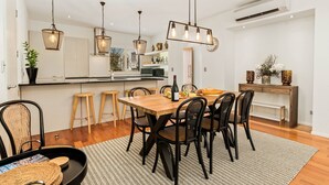 Une cuisine moderne avec une table à manger en bois, des chaises noires et des luminaires suspendus.