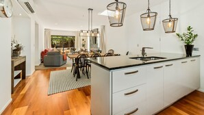Une cuisine moderne dotée d’un îlot central, de luminaires suspendus et d’un coin repas offrant une vue agréable.