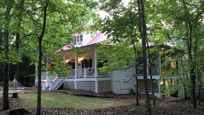 A two-story house with a porch, surrounded by trees.
