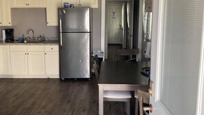 A kitchen with wooden cabinets, a stainless steel refrigerator, and a dining table with chairs.