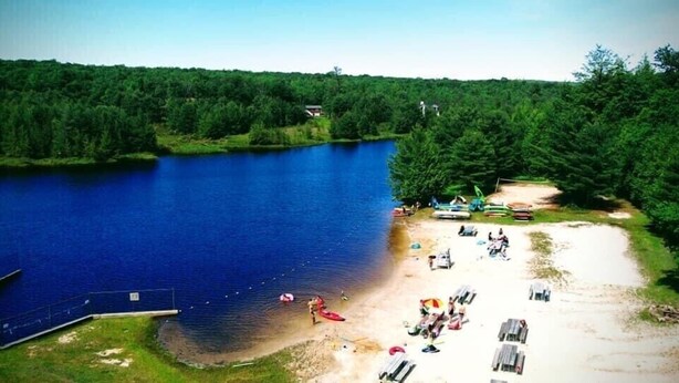 A lakeside area with a dock, boats, and beach chairs. - Jim Thorpe minutes away! Cozy Cabin, Peace & Quiet in Private Lake Community! (Jim Thorpe)