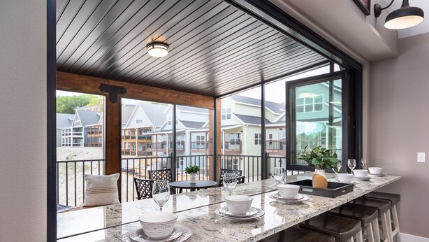 A modern kitchen with a large island, bar stools, and a view of neighboring houses. - Putting Green,  Lakeviews, Indoor Pool,Pickleball (Branson)