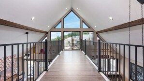 A spacious interior with a high ceiling, wooden beams, and a central staircase leading to an outdoor area. - Putting Green,  Lakeviews, Indoor Pool,Pickleball (Branson)
