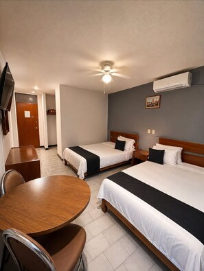 A hotel room with two beds, a dining table, chairs, a ceiling fan, and an air conditioning unit. - Hotel Italia Aguascalientes (Aguascalientes)