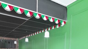 A restaurant interior with green walls, red leather booths, and wooden tables. - Hotel Italia Aguascalientes (Aguascalientes)
