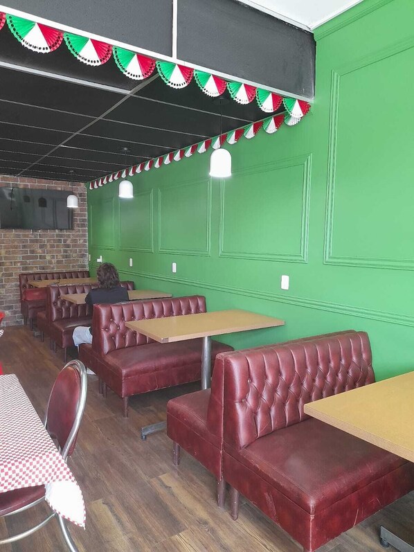 A restaurant interior with green walls, red leather booths, and wooden tables. - Hotel Italia Aguascalientes (Aguascalientes)