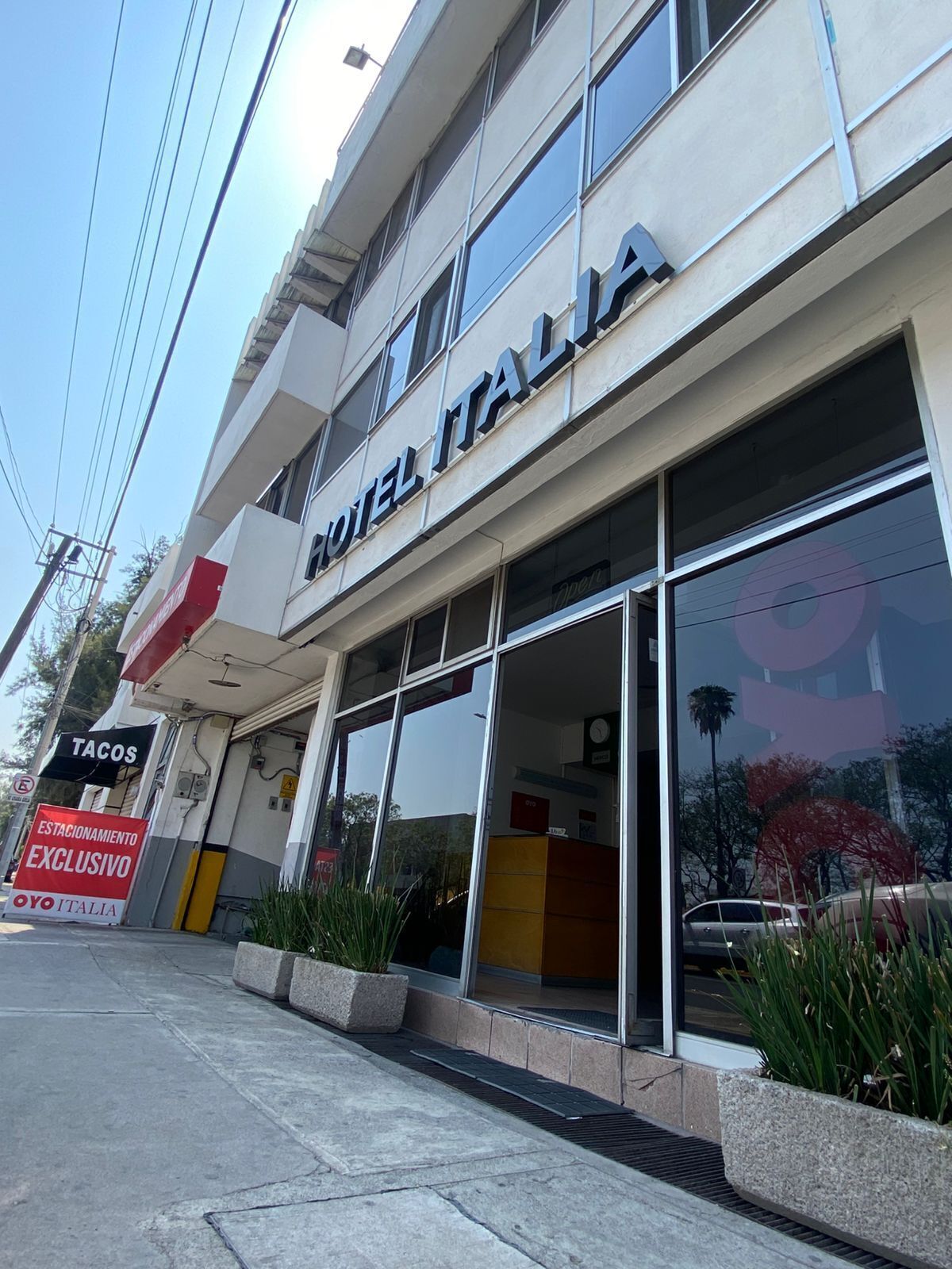 A hotel named "HOTEL ITALIA" with a sign indicating "TACOS" and a "YOO ITALIA" sign.
