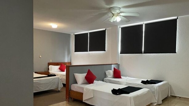 A hotel room with two single beds, a ceiling fan, and large windows. - Hotel Italia Aguascalientes (Aguascalientes)