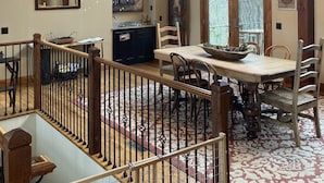 A spacious dining area with a high ceiling and large windows, wooden beams, and a view of the outdoors.