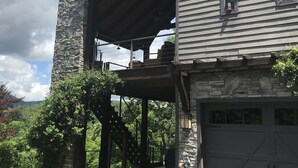 A two-story house with a stone chimney, a covered porch, and a garage.