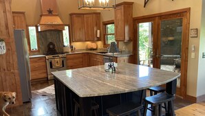 A kitchen with wooden cabinets, a large island with stools, a gas stove, and a built-in oven.