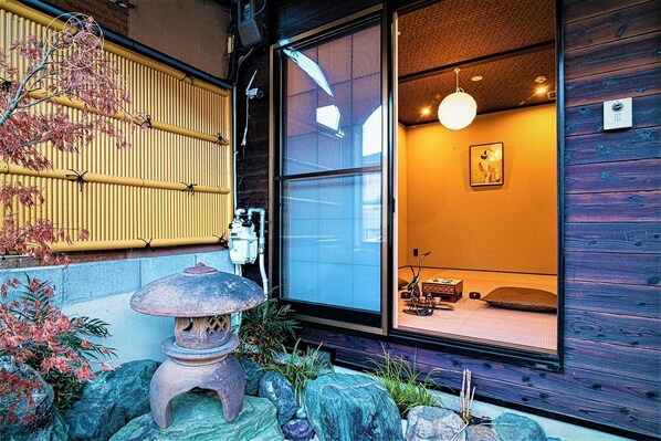A traditional Japanese room with tatami mats, a shoji screen, a stone lantern, and a hanging light fixture.