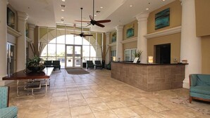 A spacious lobby with a reception desk, seating area, and large windows.