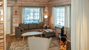 Un acogedor interior de cabaña con un sofá, una mesita y un televisor.