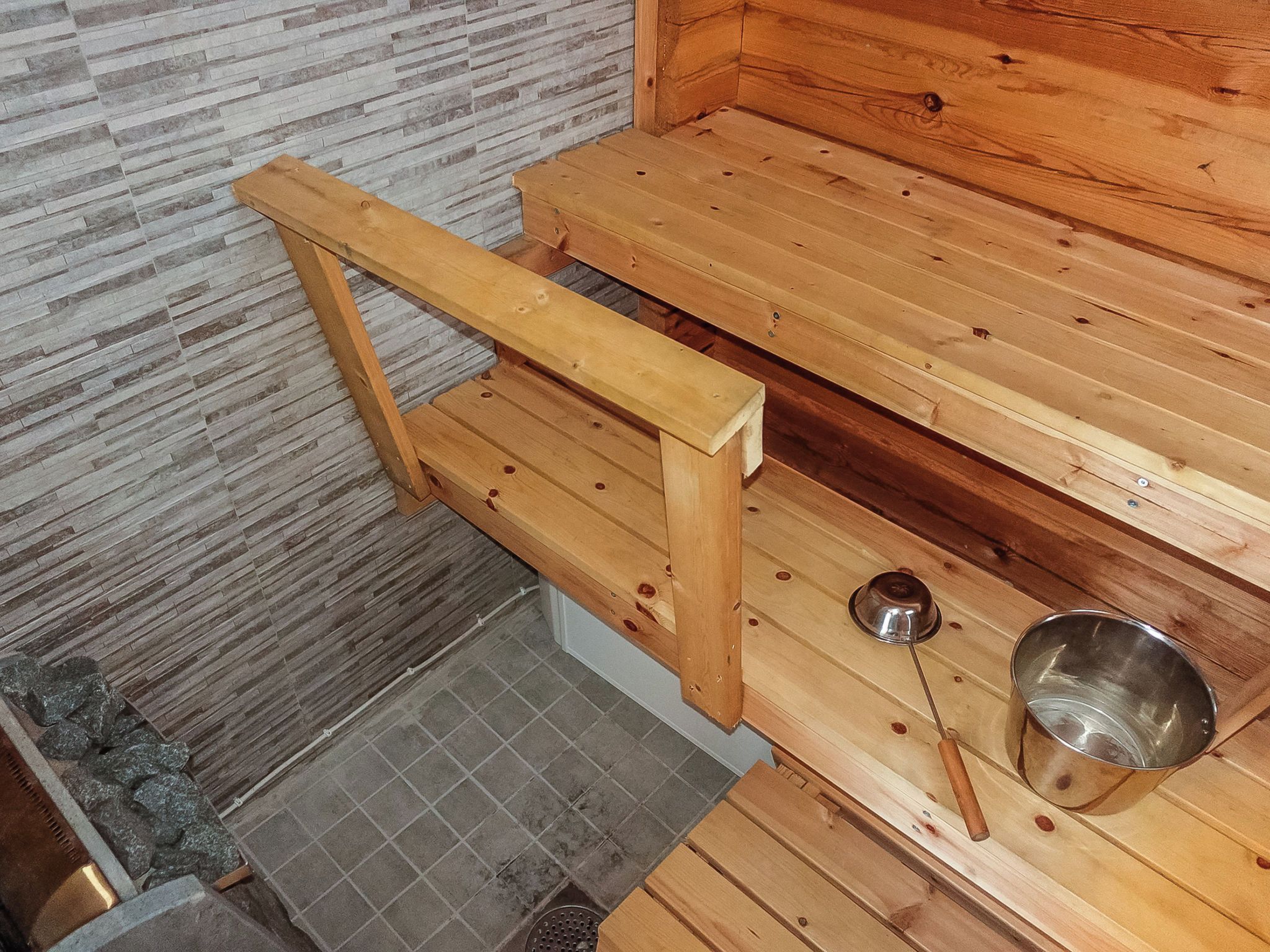 A sauna with wooden benches and a metal basin.
