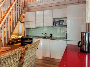 A compact kitchen with white cabinets, a microwave, and a red countertop.