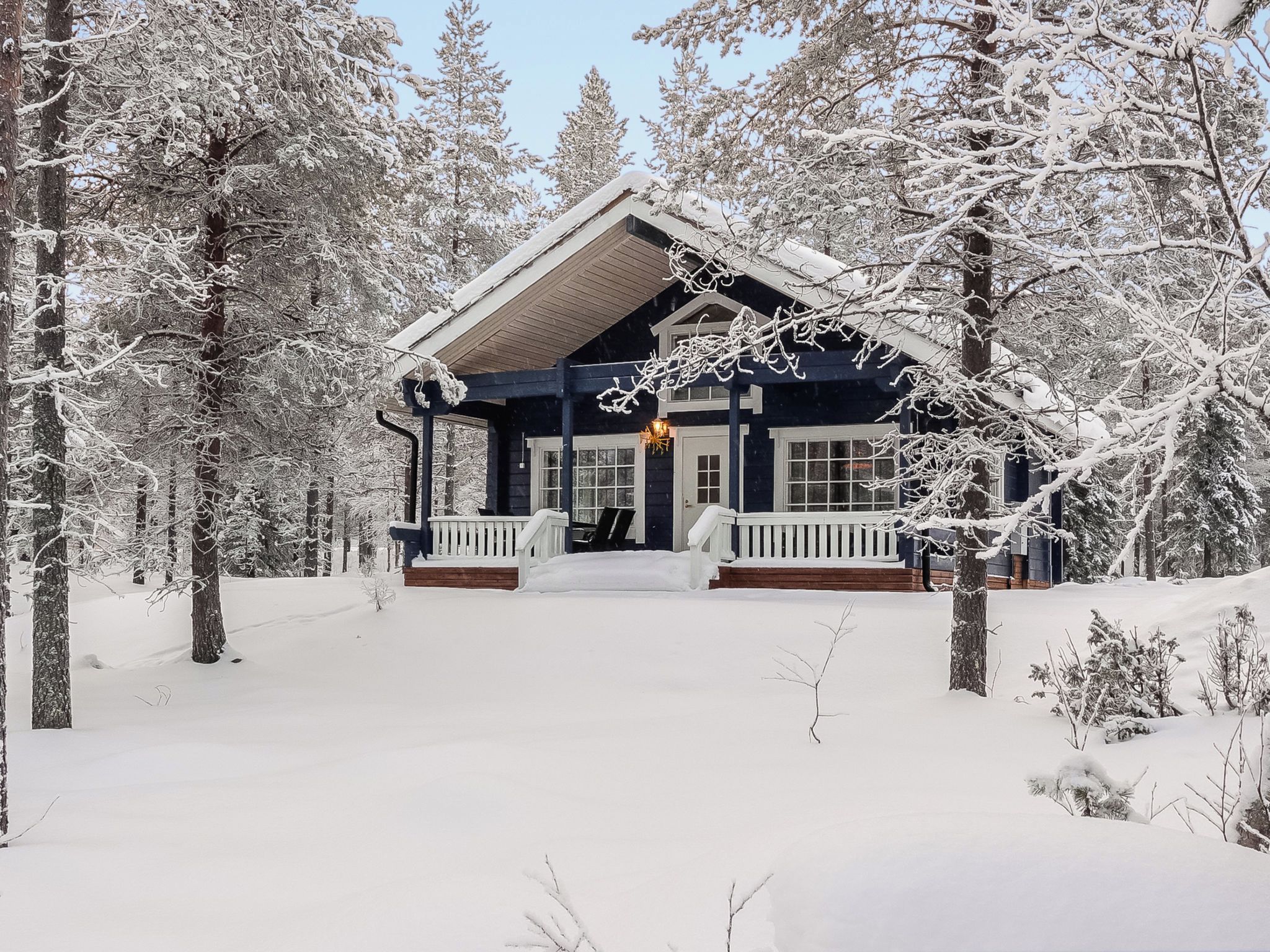 A snow-covered lodge with a porch and a chimney.
