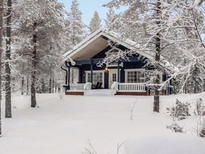 A snow-covered lodge with a porch and a chimney.