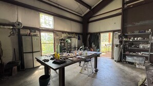 A spacious room with a large workbench, a refrigerator, and a window providing natural light. - Bird Lodge Tipi at Stepping Stone (Bigfork)