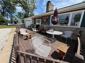 A deck with outdoor seating, including chairs and tables, and a covered area with an umbrella.