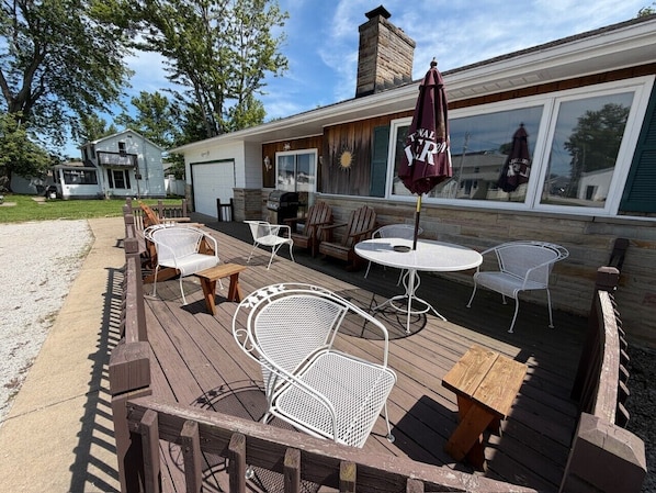 A deck with outdoor seating, including chairs and tables, and a covered area with an umbrella.