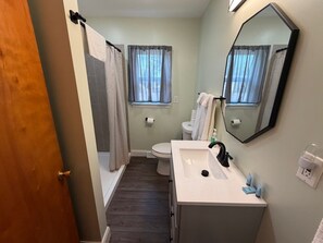 A bathroom with a toilet, sink, mirror, and shower curtain.