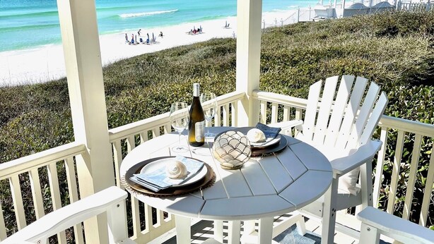 Un espacio al aire libre cubierto con una mesa lista para dos personas, con vista a la playa.