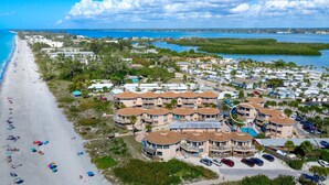 A coastal resort with beachfront villas, a sandy beach, and a marina.