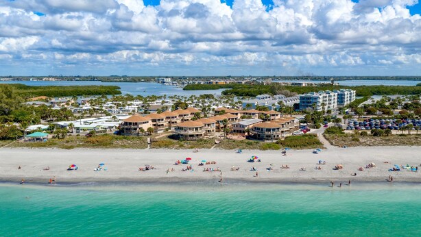 A coastal resort with beachfront villas, a sandy beach, and a marina.