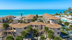 A beachfront resort with multiple-story buildings, a pool, and a beach view.