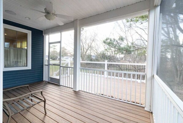 Enjoy the serene view from this covered porch with a wooden deck and comfortable seating area.