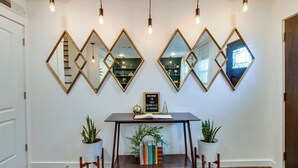Un espace d’accueil avec un bureau en bois, deux plantes en pot et un panneau d’accueil.