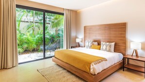 A bedroom with a large bed, wooden headboard, and a view of a lush garden through a sliding glass door. - Apartment With Private Plunge Pool - Ground Floor by Sessile (Tulum)