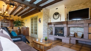 A cozy living room with a fireplace, a sofa, and a dining area with a table and chairs.