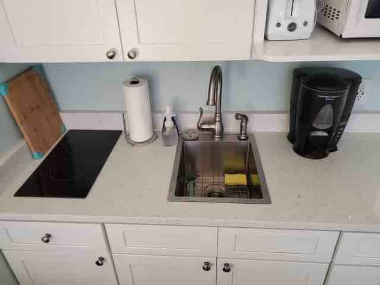 A kitchen with a sink, a microwave, a coffee maker, and a roll of paper towels.