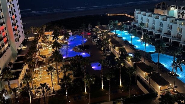 Resort com várias piscinas, palmeiras e vista para a praia.