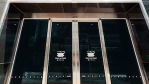 The entrance of Henn na Hotel with a modern glass facade and a sign in both English and Japanese.