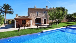Une villa en pierre dotée d’une piscine, d’un espace extérieur aménagé et d’une pelouse bien entretenue.