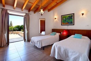 Two single beds with white bedding and a wooden headboard, set against a large window with a view of the outdoors.