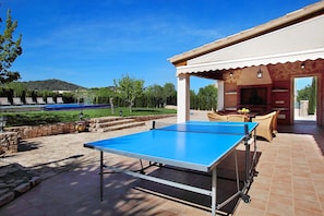 Relax in a serene outdoor space with a ping pong table, surrounded by a stone wall and lush greenery.
