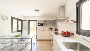 Une cuisine moderne avec une table à manger en verre, des appareils électroménagers en acier inoxydable et un grille-pain rouge.