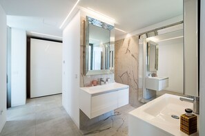 A modern bathroom with a large mirror, two sinks, and a bathtub.
