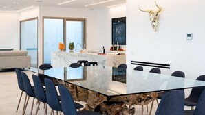 Een moderne keuken met een marmeren aanrechtblad, een stierenhoofd decoratie, en een glazen eettafel met stoelen.