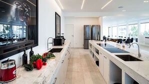 Een moderne keuken met een groot eiland, roestvrijstalen apparatuur en uitzicht op de omgeving.
